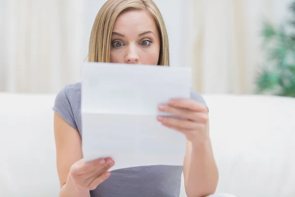 Döbbenve nő nappaliban levelet olvasó — Stock Fotó