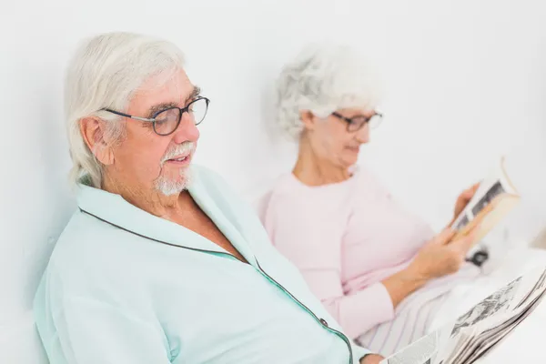 Mann und Frau lesen im Bett — Stockfoto