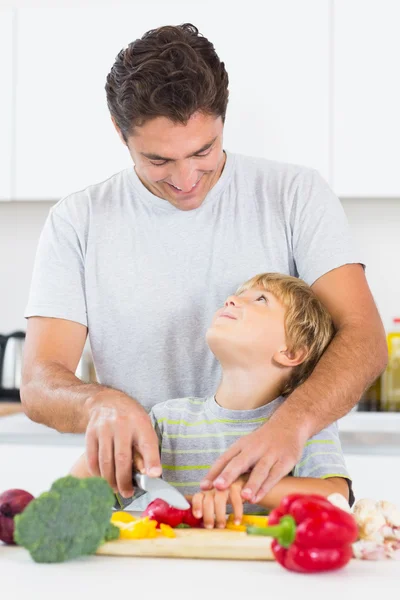 Père et fils se regardent en train de couper des légumes — Photo