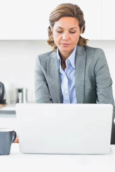 Mulher usando laptop na cozinha — Fotografia de Stock