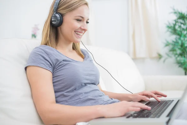 Vrouw luisteren muziek via de koptelefoon terwijl het gebruiken van laptop — Stockfoto