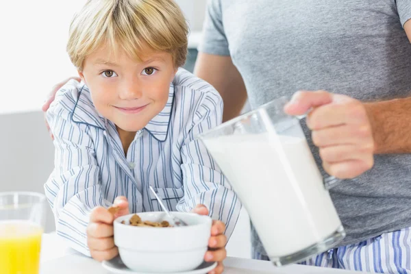 Far hälla mjölk för söner spannmål — Stockfoto