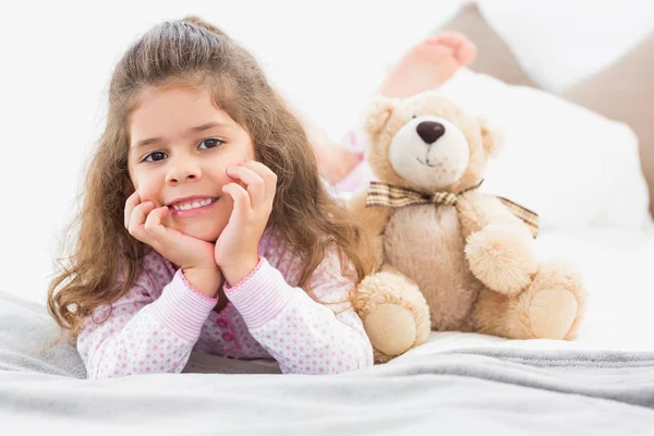 Meisje liggend op bed met teddy bear — Stockfoto