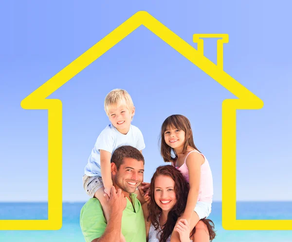 Smiling family posing with a yellow house illustration — Stock Photo, Image