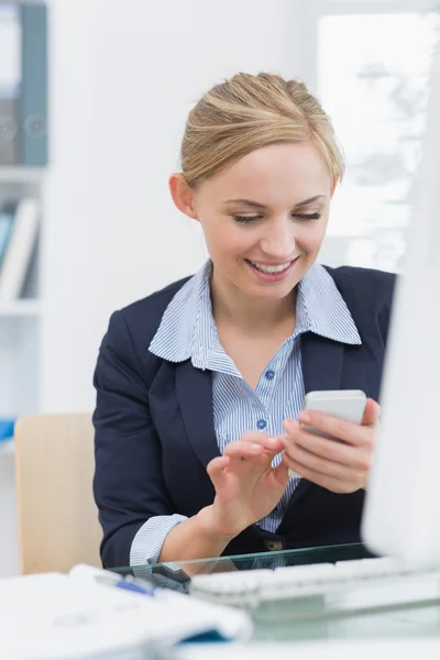 Young business woman text messaging at office desk — Stock Photo, Image