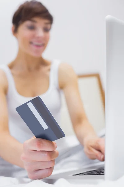 Smiling woman shopping online on bed — Stock Photo, Image