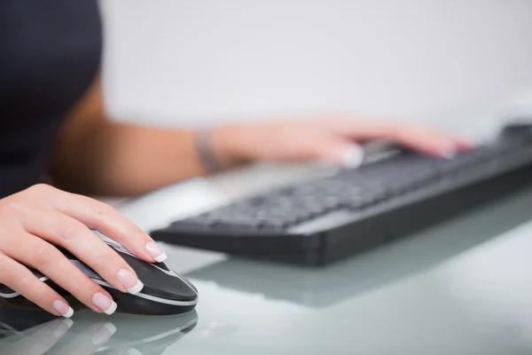 Vrouw met behulp van computermuis en toetsenbord aan balie — Stockfoto
