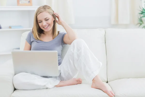 Ontspannen gelukkig vrouw met behulp van laptop op sofa — Stockfoto