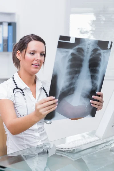 Doctor with x-ray sitting in front of computer at clinic — Stock Photo, Image