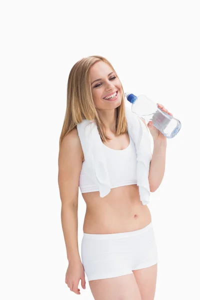 Happy young woman with towel around neck holding water bottle — Stock Photo, Image