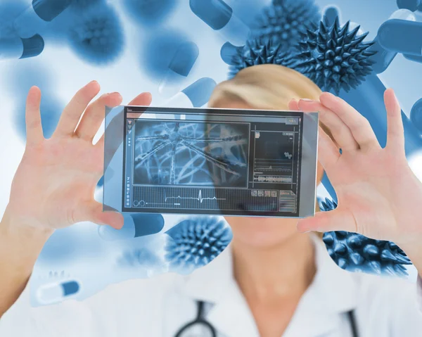 Happy blonde nurse holding a virtual screen Stock Picture