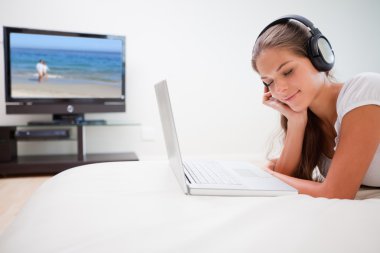 Woman enjoying music on her laptop clipart