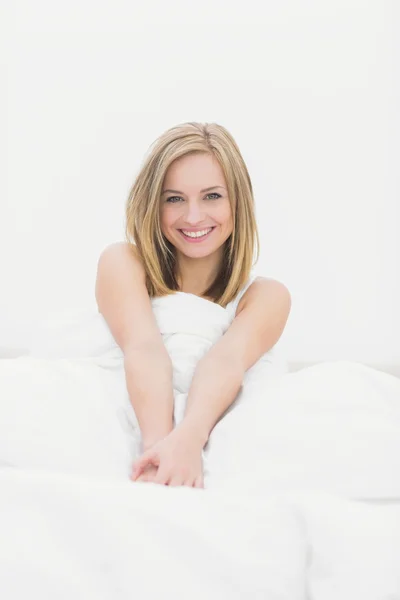 Portrét smějící se ženu sedící v posteli — Stock fotografie