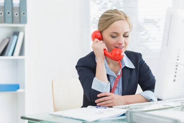 Ejecutiva usando teléfono fijo rojo en el escritorio — Foto de Stock