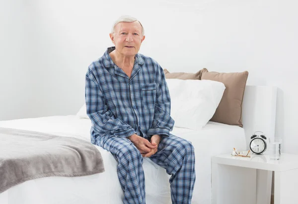 Älterer Mann sitzt auf seinem Bett — Stockfoto