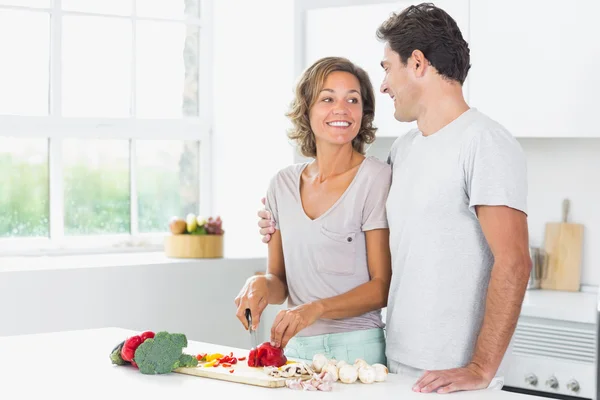 Man vrouw omarmen als ze zich groenten voorbereidt — Stockfoto