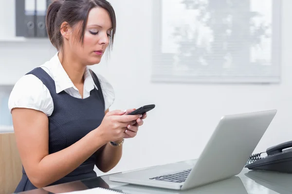 Mensagens de texto mulher de negócios na frente do laptop — Fotografia de Stock