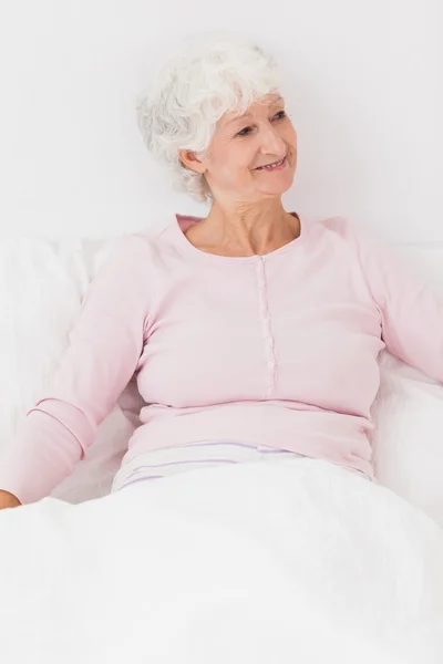 Glückliche Frau sitzt im Bett — Stockfoto