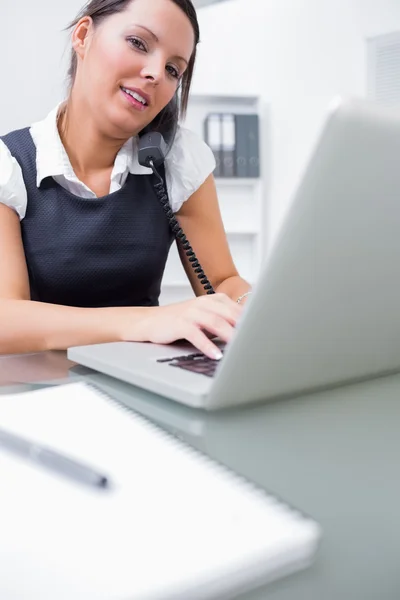 Biznes kobieta przy użyciu telefon stacjonarny i laptop — Zdjęcie stockowe