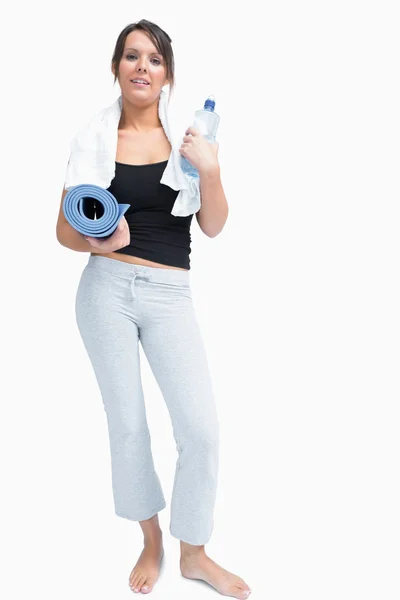 Retrato de mulher em sportswear segurando garrafa de água e tapete — Fotografia de Stock