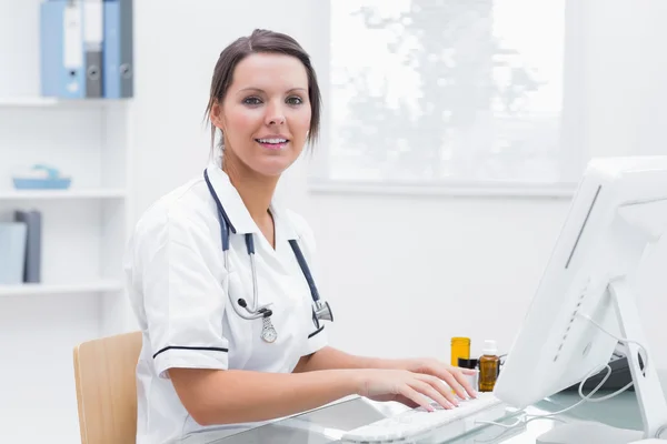 Smiling female nurse using computer at clinic — Stock Photo, Image