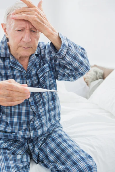 Old man taking his temperature — Stock Photo, Image