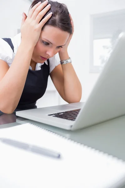 Boos uitvoerend met hoofd in handen in de voorkant van de laptop op kantoor — Stockfoto