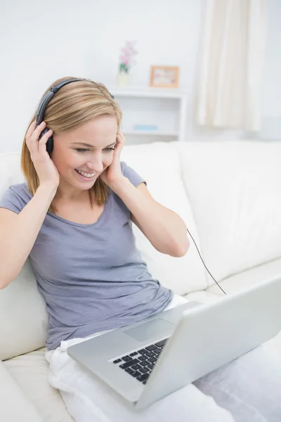 Щаслива жінка слухає музику через навушники з ноутбуком — стокове фото