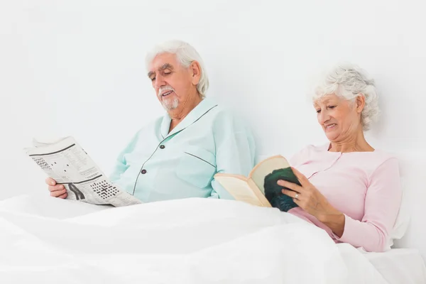 Sorrindo casal leitura na cama — Fotografia de Stock