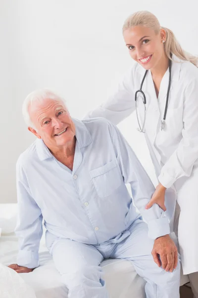 Médico sonriente ayudando al hombre a sentarse —  Fotos de Stock