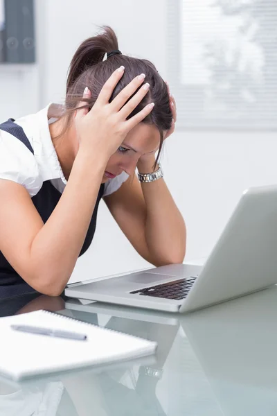 Femme d'affaires avec la tête dans les mains devant l'ordinateur portable au bureau — Photo