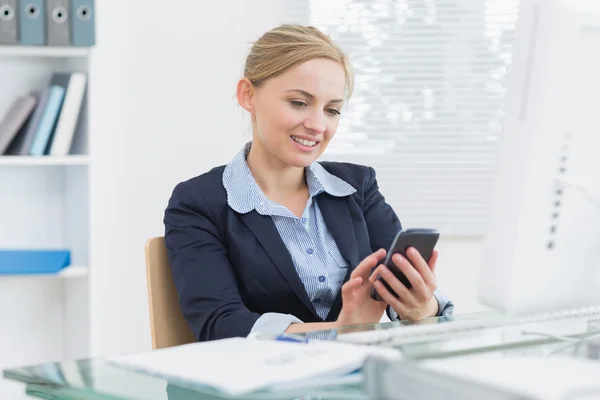 Young business woman text messaging office desk — Stock Photo, Image