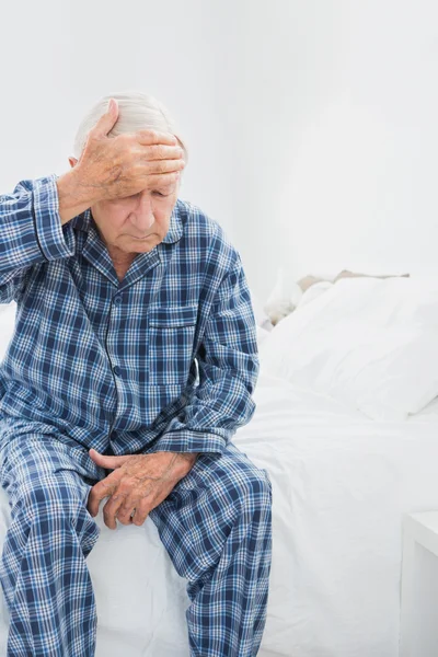 Oude man lijden op het bed — Stockfoto