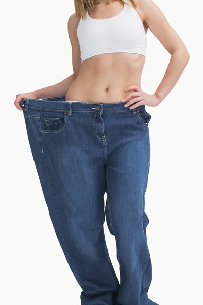 Mladá žena nosí staré kalhoty po hubnutí — Stock fotografie