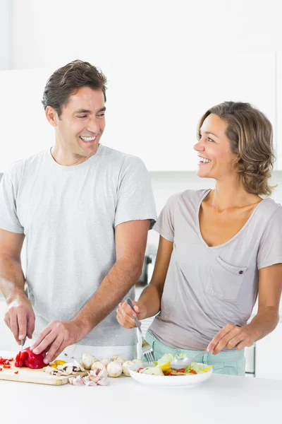 Sonriente pareja haciendo ensalada juntos —  Fotos de Stock