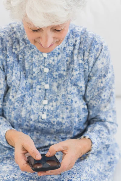 Oudere lachende vrouw met behulp van een smartphone — Stockfoto