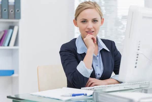 Confident business woman with computer at office desk — Stok fotoğraf