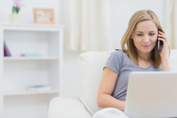 Mujer casual usando portátil y teléfono celular en casa — Foto de Stock