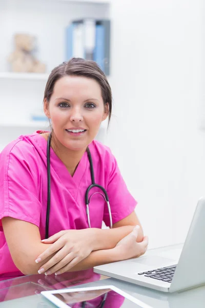 Portret van lachende verpleegster met laptop bij kliniek — Stockfoto