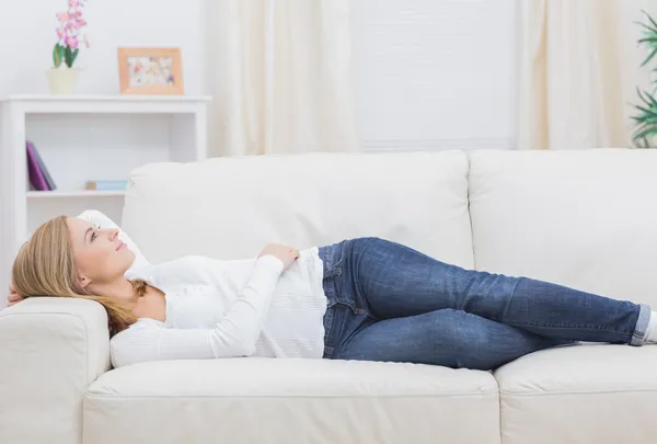 Casual thoughtful woman lying on sofa — Stock Photo, Image