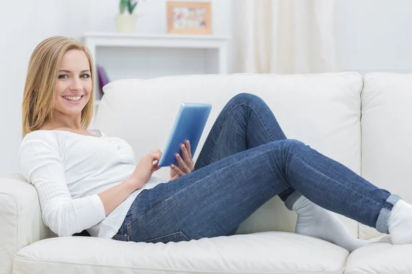 Portret van gelukkig casual vrouw met behulp van digitale Tablet PC op sofa — Stockfoto