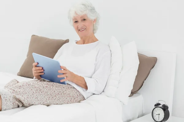 Femme âgée souriante utilisant une tablette numérique — Photo