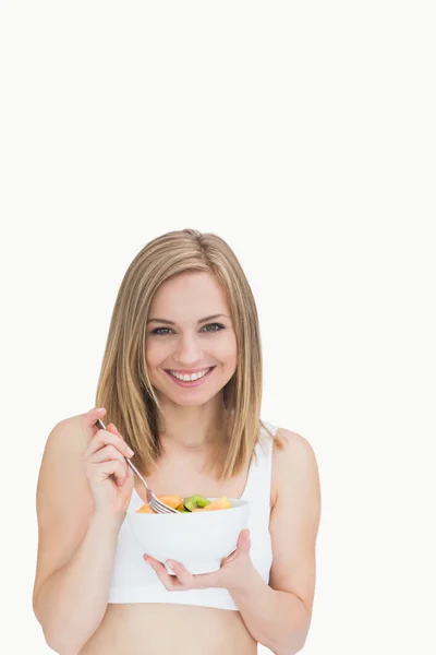 Portrait of young woman with fork and bowl of fruits — Stock Photo, Image