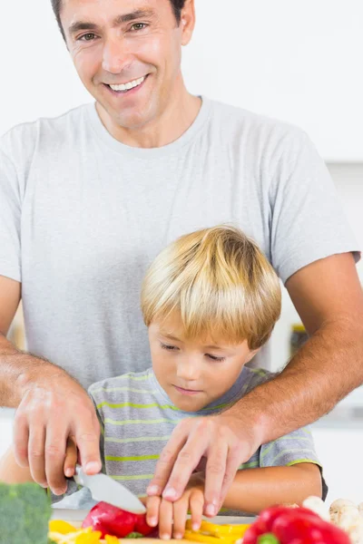 Father helping son to slice vegetables — Stock Photo, Image