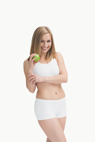 Porträt einer glücklichen jungen Frau, die einen grünen Apfel zeigt — Stockfoto