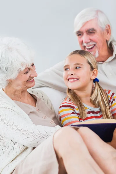 Happy grandparents reading with granddaughter — Stock Photo, Image