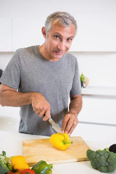 Uomo felice che taglia un pepe giallo — Foto Stock