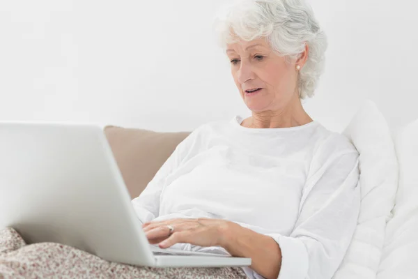 Mulher velha digitando em seu laptop — Fotografia de Stock