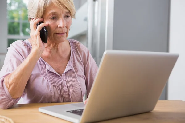 Donna focalizzata utilizzando il suo computer portatile e chiamando — Foto Stock