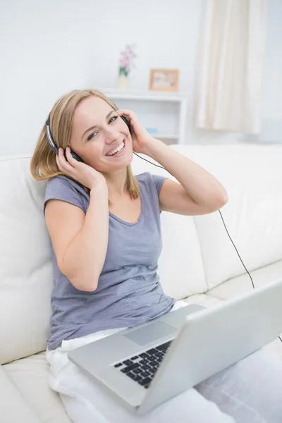 Happy woman listening music through headphones with laptop — Stock Photo, Image
